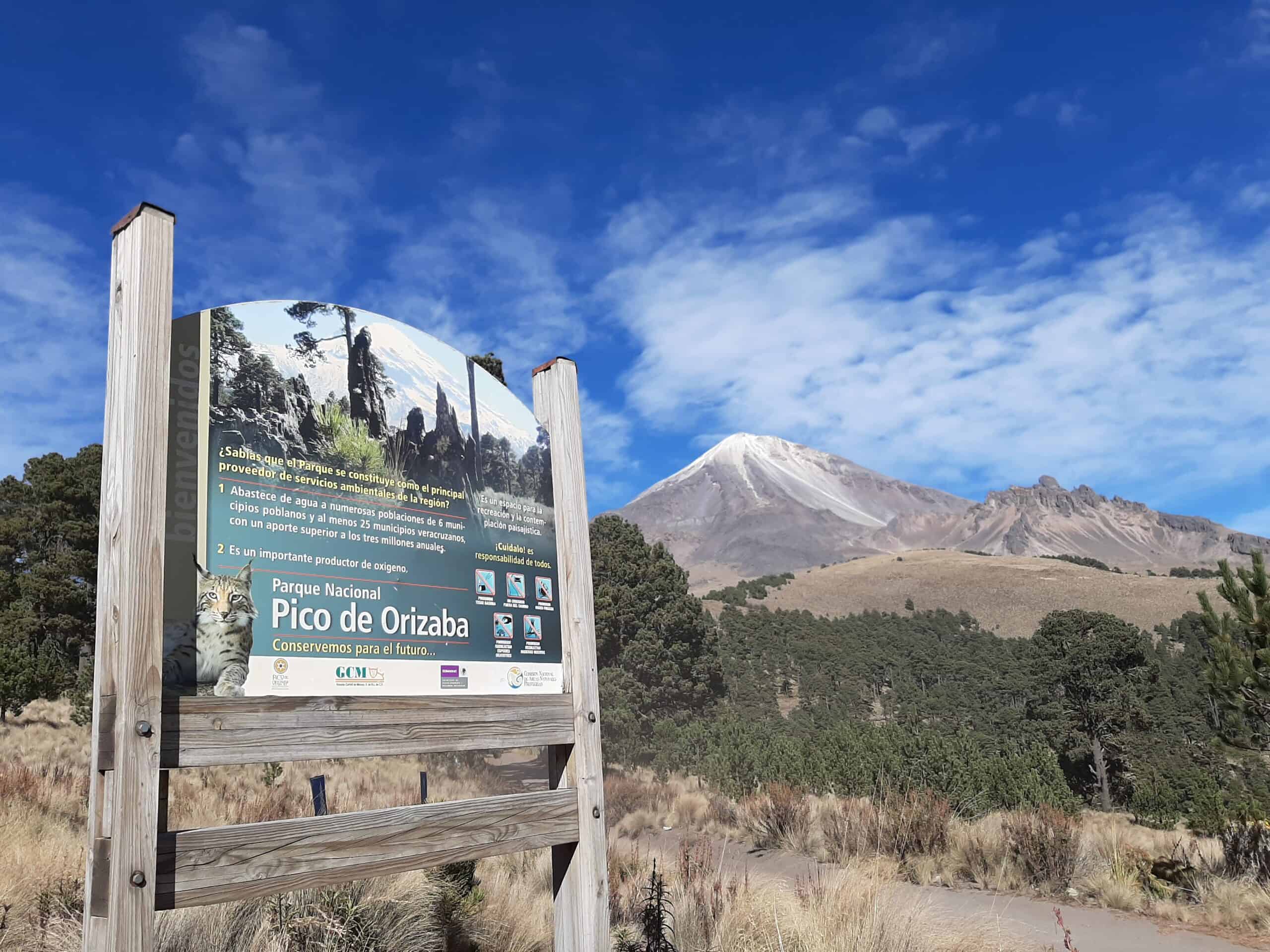Parque Nacional Pico de Orizaba entrance sign with the snow-capped volcano visible in the background