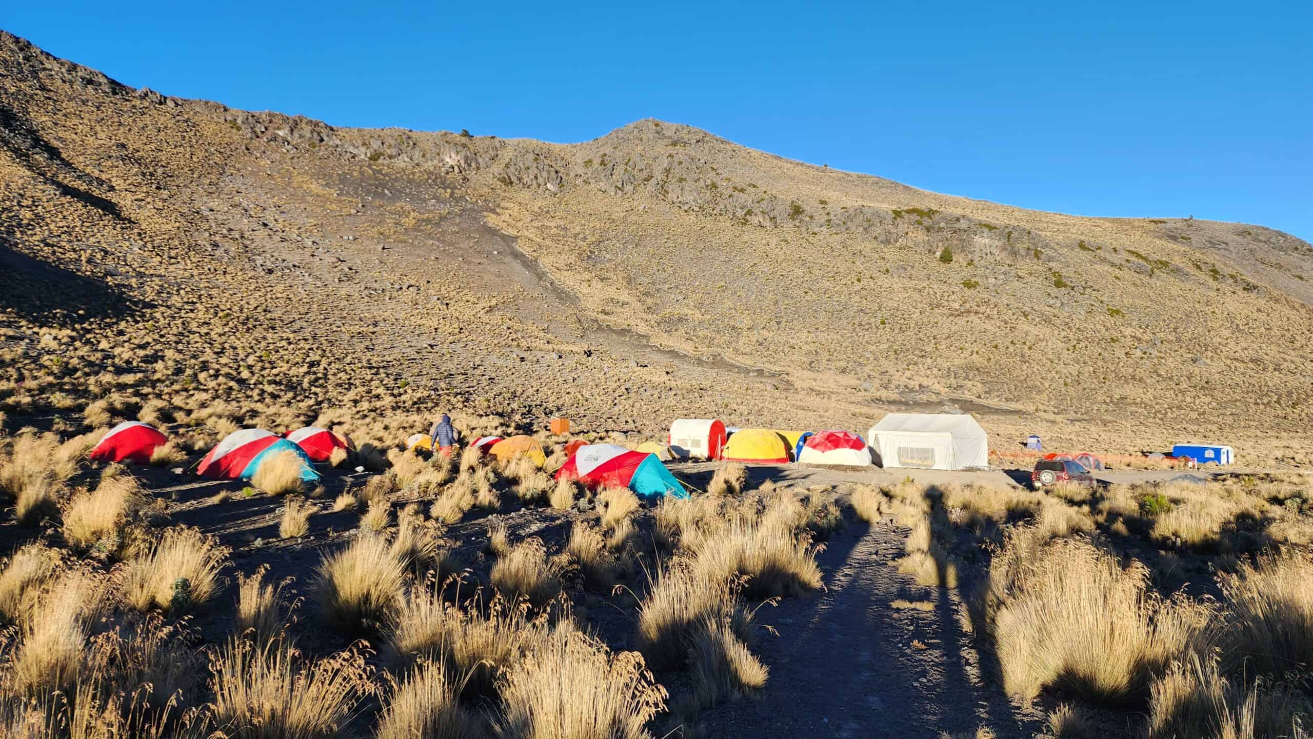 Colorful tents at the base camp on Pico de Orizaba, with the dining tent and support vehicles near the trailhead below the volcano's high plateau