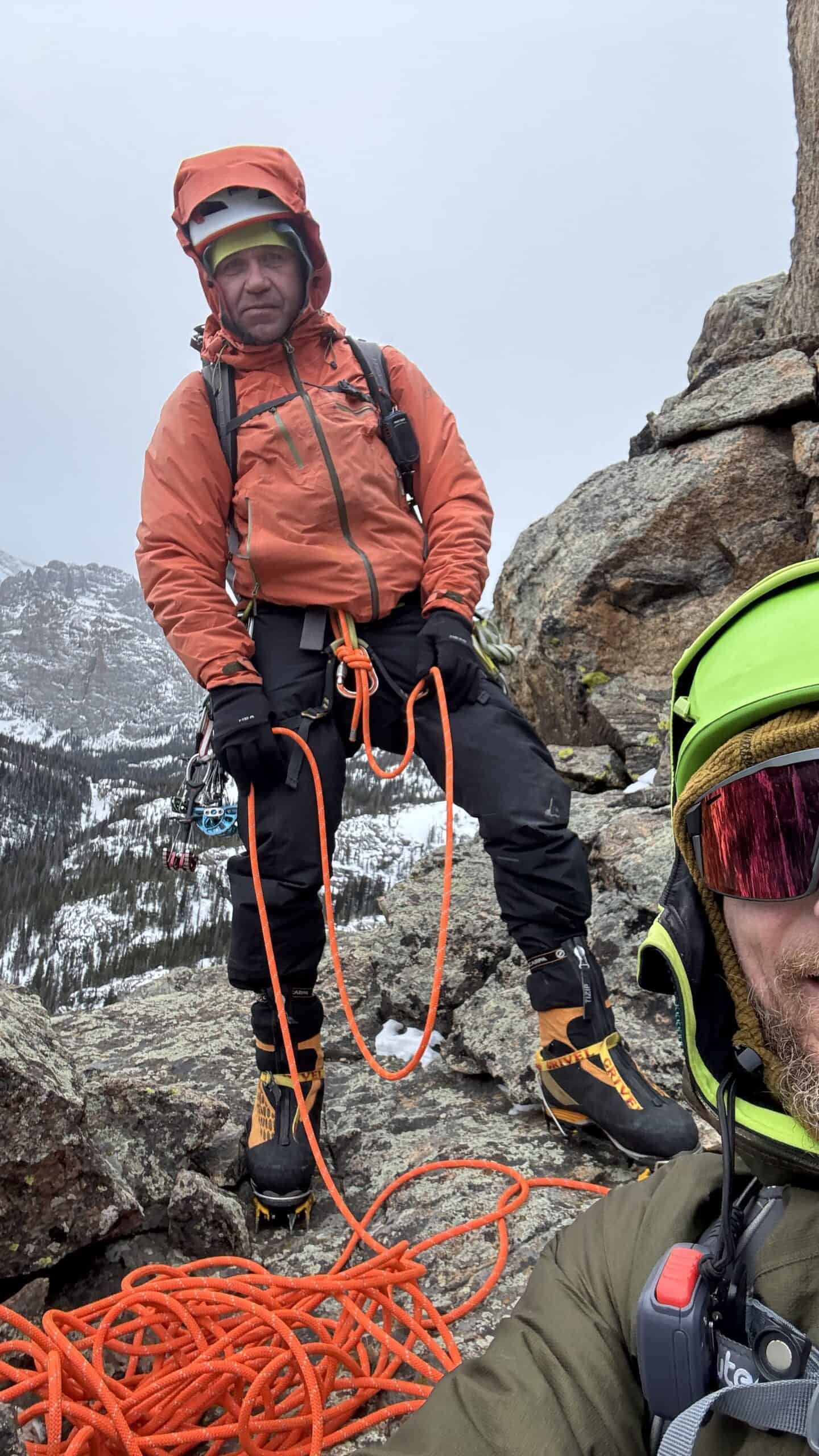 Climber coiling rope on a rocky alpine ridge in crampons during a Basic Mountaineering Course